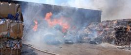 Zdjęcie przedstawia palące się baloty sprasowanej makulatury, trwają działania gaśnicze