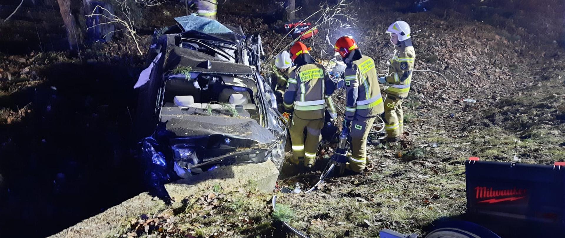 Śmiertelny wypadek na DK 74. Strażacy sprawdzają wrak auta.