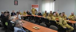 Podczas narady prowadzi prezentację Zastępca Komendanta Powiatowego w Ostrowcu Św. Widok wszystkich uczestników spotkania oglądających prezentację. 