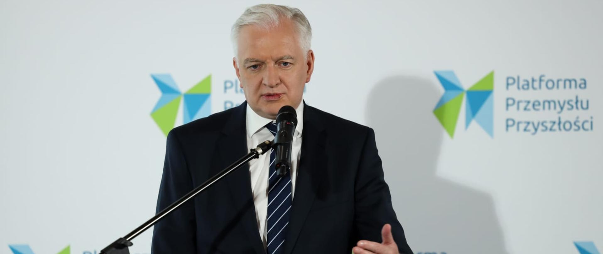 Premier Jarosław Gowin stoi za pulpitem i przemawia do ludzi na konferencji zorganizowanej przez Platformę Przemysłu Przyszłości
