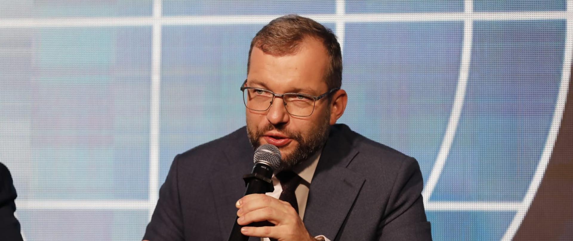 Minister funduszy i polityki regionalnej Grzegorz Puda przemawia podczas panelu dyskusyjnego na Forum w Karpaczu. Na pierwszym planie mężczyzna z mikrofonem.