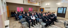 Na zdjęciu członkowie lokalnej jednostki OSP w umundurowaniu strażackim siedzą uczestniczą w zebraniu