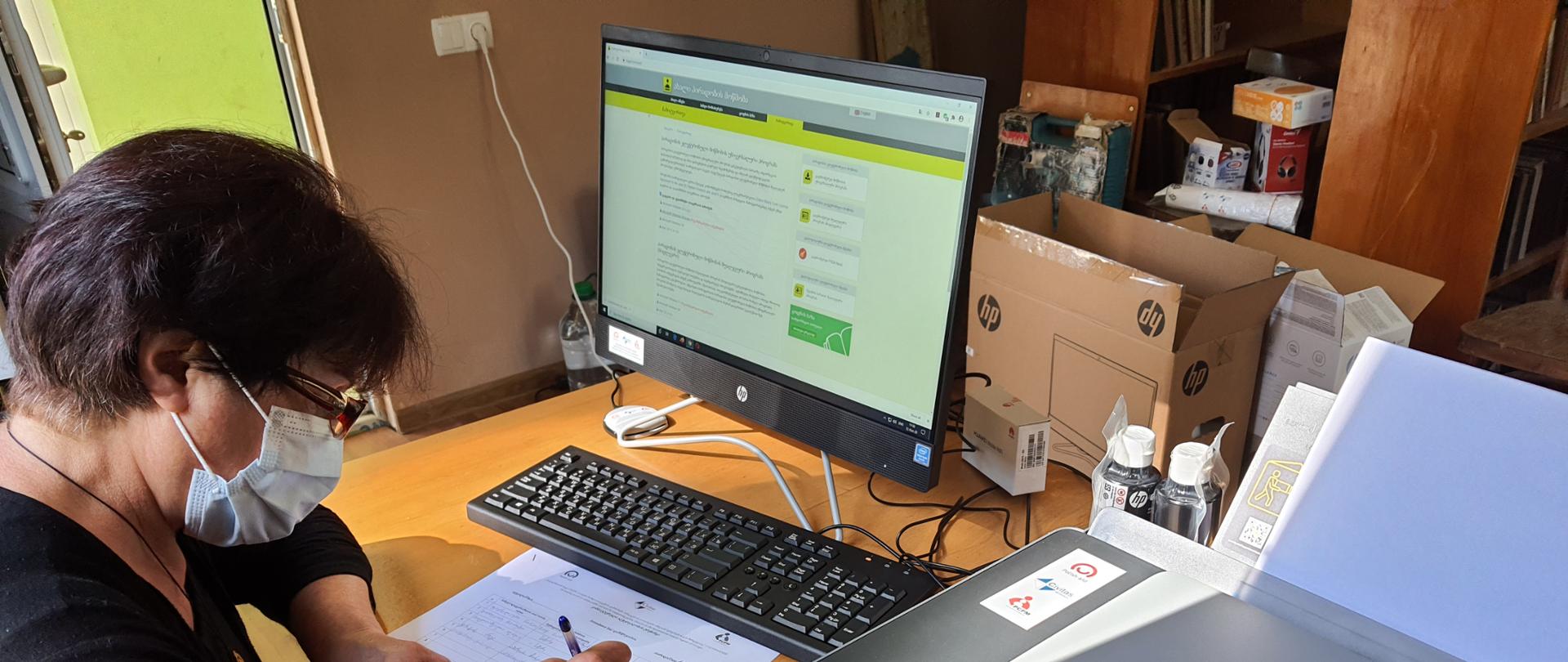 kobieta wypełnia dokumenty związane z przekazaniem komputera dla biblioteki