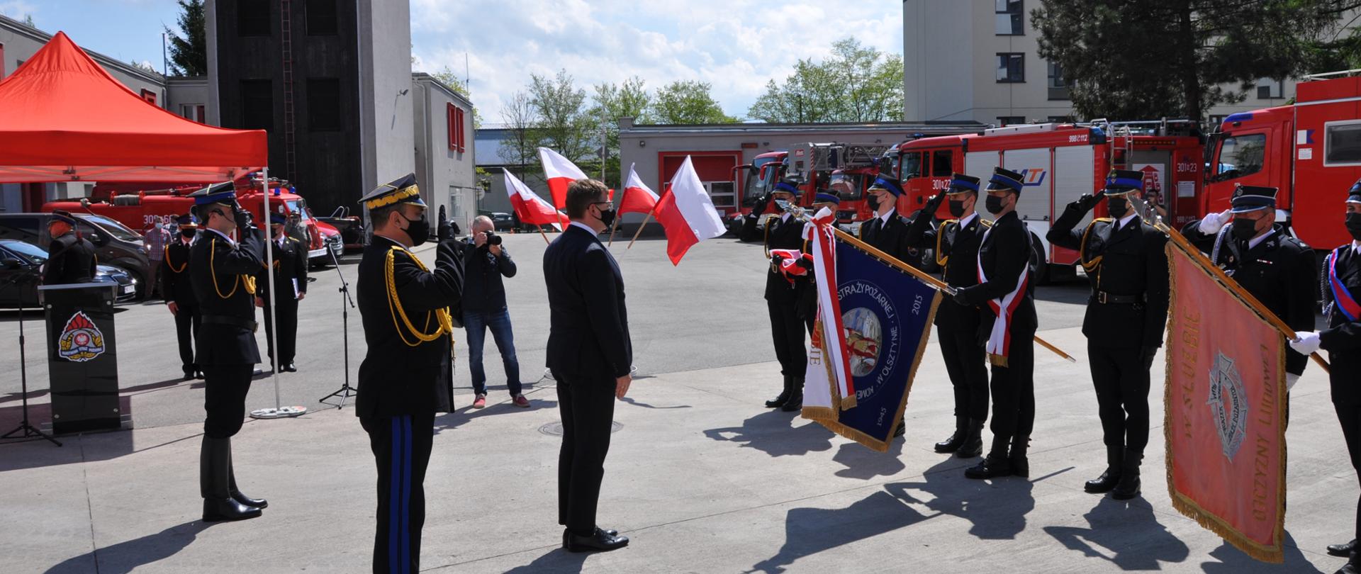 Zdjęcie przedstawia przywitanie sztandaru Komendy Miejskiej Państwowej Straży Pożarnej w Olsztynie oraz sztandaru Ochotniczej Straży Pożarnej w Świątkach. Powitania dokonali: Pan Artur Chojecki - Wojewoda Warmińsko-Mazurski oraz nadbryg. Tomasz Komoszyński - Warmińsko-Mazurski Komendant Wojewódzki PSP. 