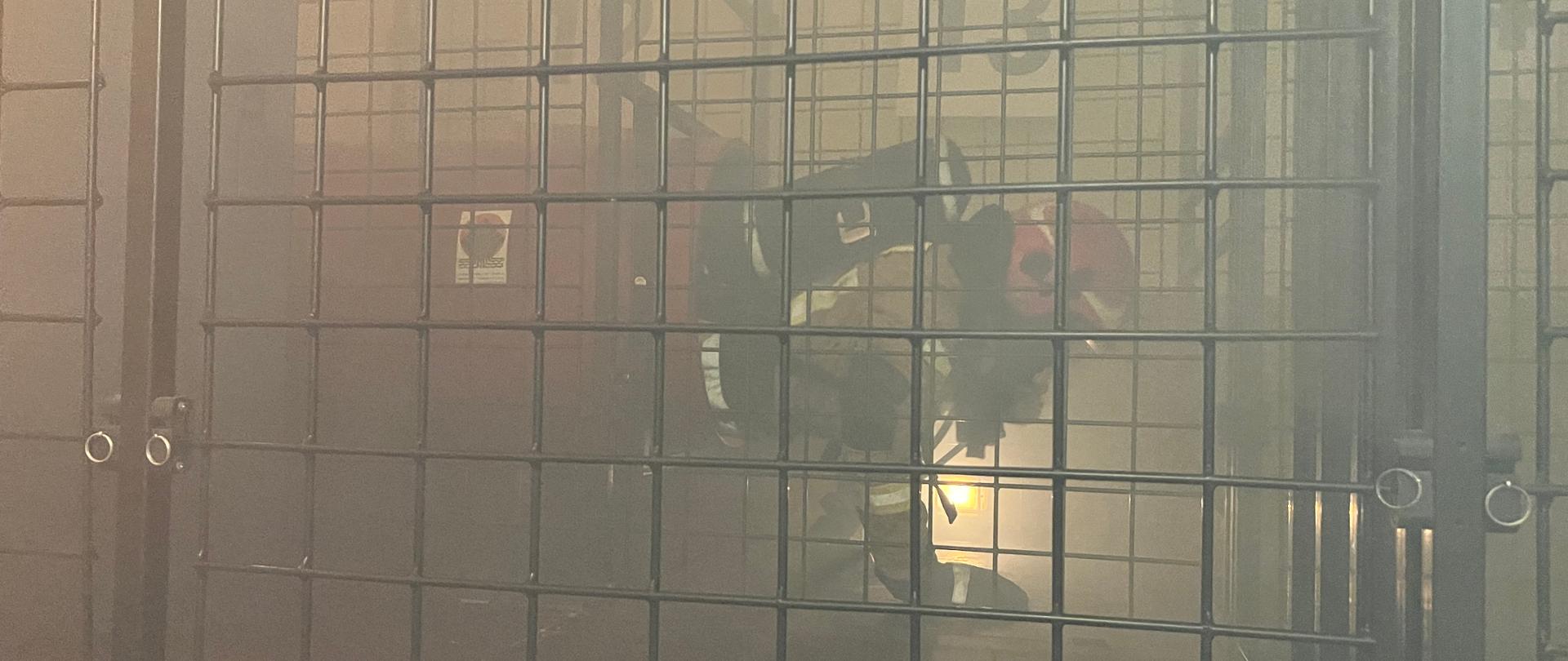 Strażak przechodzi test w komorze dymowej w pełnym umundurowaniu.