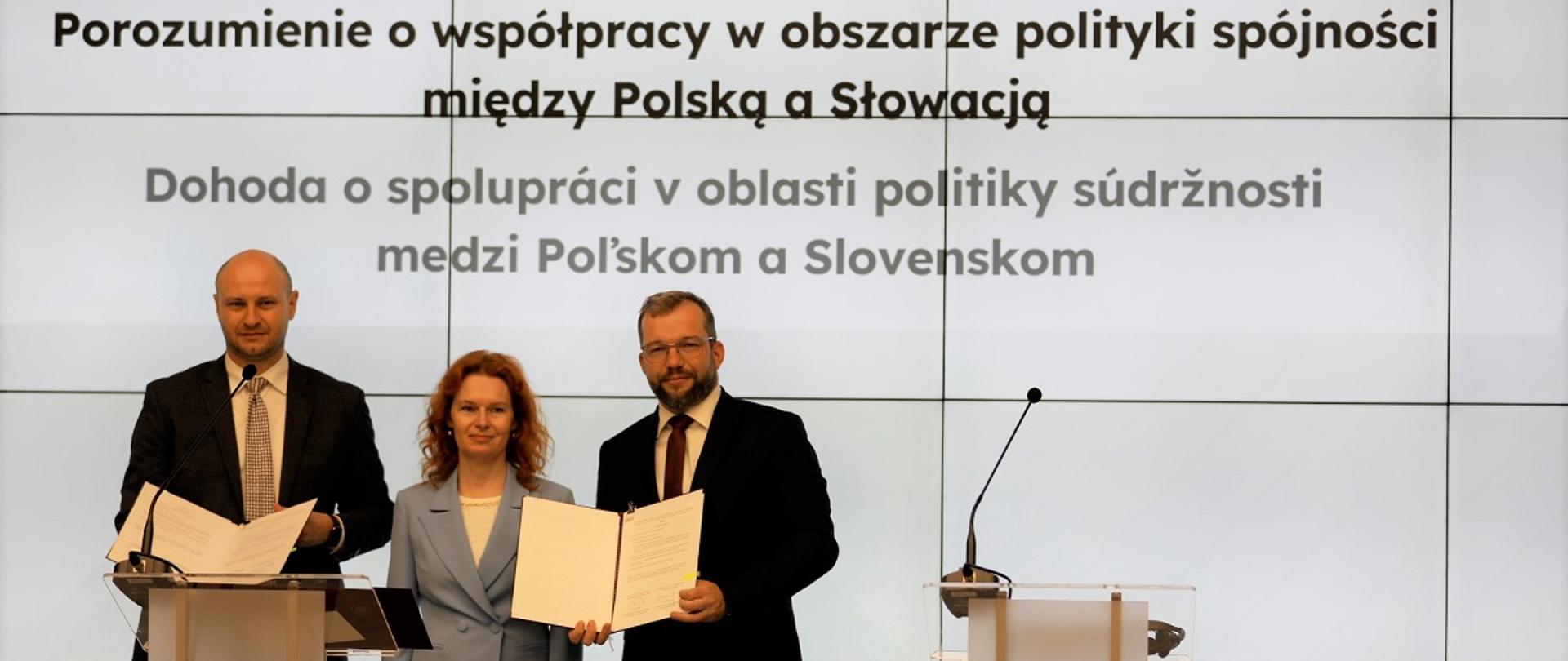 Minister funduszy i polityki regionalnej Grzegorz Puda stoi i trzyma w dłoniach dokument porozumienia o współpracy w obszarze polityki spójności między Polską a Słowacją, po lewej od niego stoi wicepremier Republiki Słowacji ds. planu odbudowy i funduszy europejskich Lívia Vašákova oraz minister inwestycji, rozwoju regionalnego i informatyzacji Republiki Słowackiej Peter Balík 
