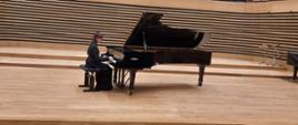 Dziewczyna gra na fortepianie na estradzie sali koncertowej.