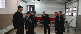 Komendant Powiatowy Państwowej Straży Pożarnej w Rypinie starszy brygadier Grzegorz Łydkowski na jednym z garaży Komendy Powiatowej Państwowej Straży Pożarnej w Rypinie gratuluje i przekazuje łódź przedstawicielom Ochotniczej Straży Pożarnej w Starym Kobrzyńcu.