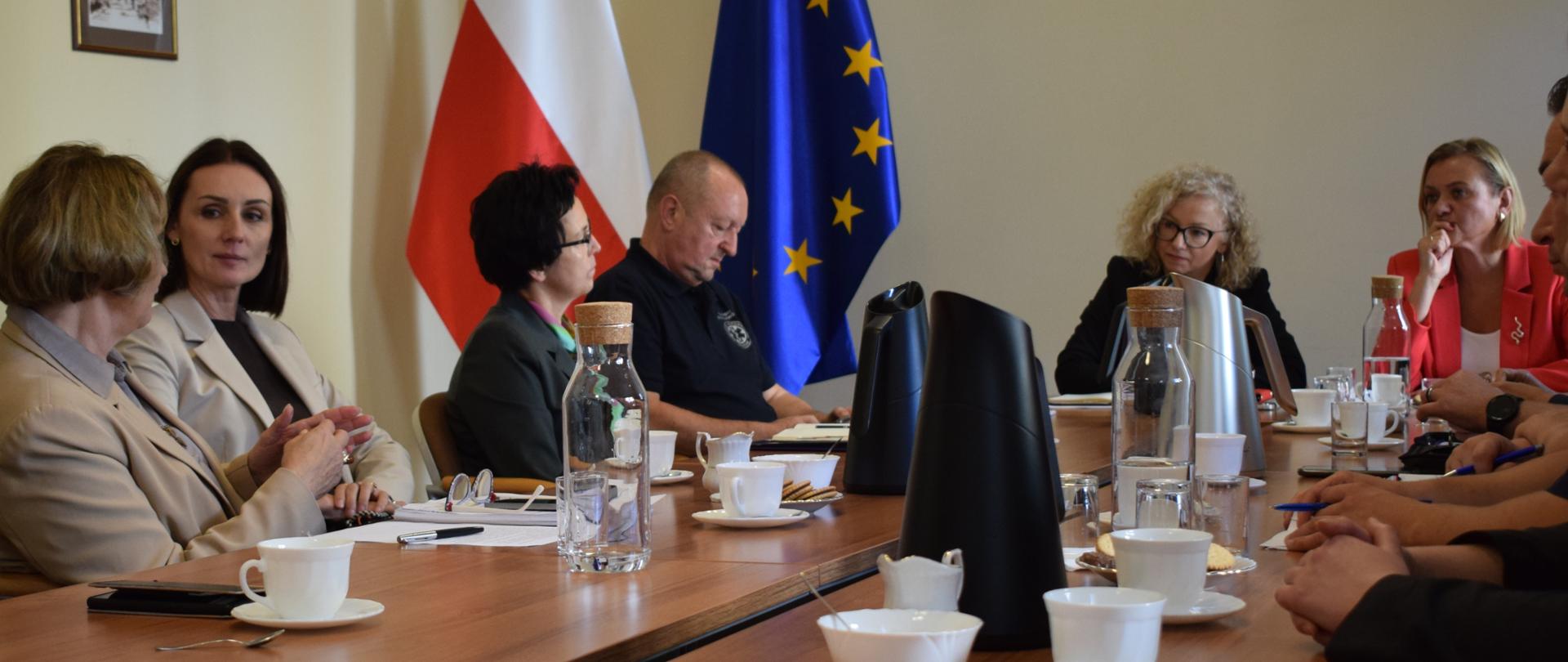 kilka osób siedzi perzy stole i rozmawia