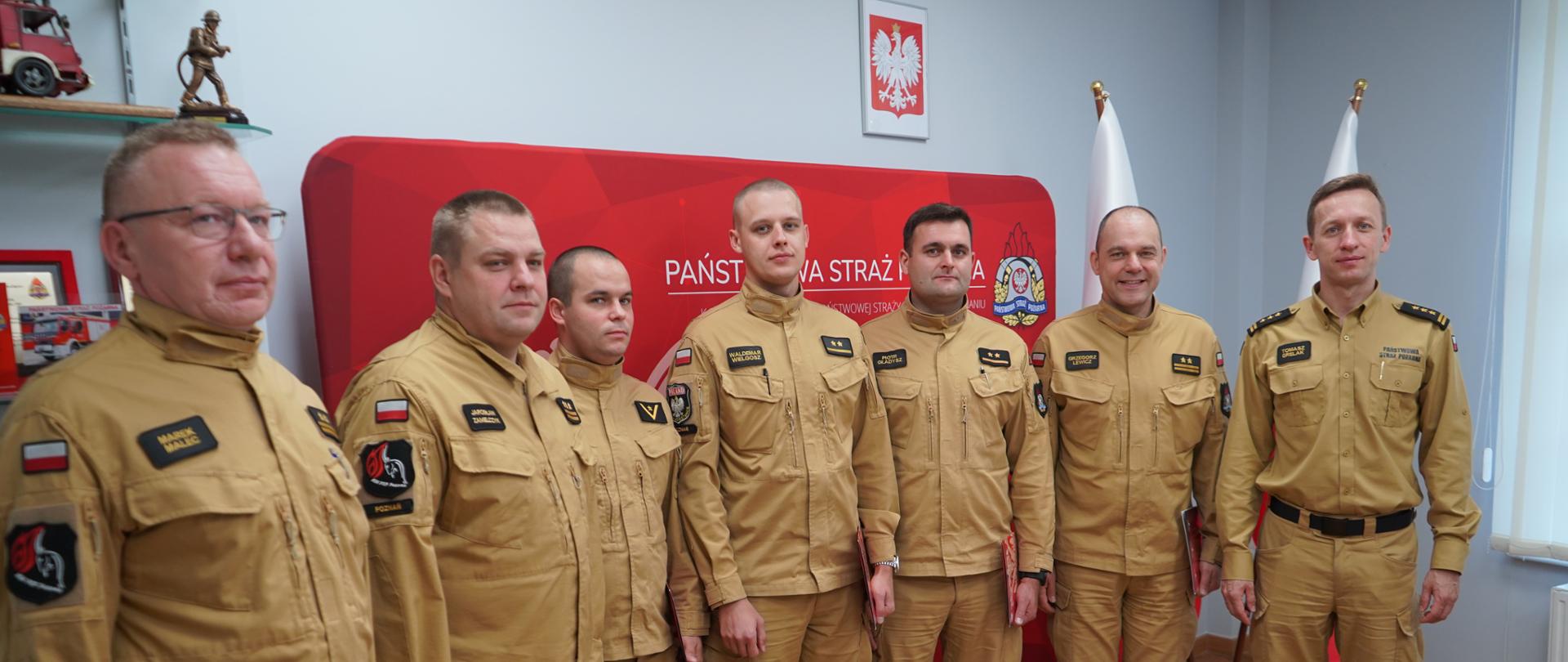 Zdjęcie przedstawia siedmiu funkcjonariuszy Komendy Wojewódzkiej PSP w Poznaniu ustawionych w pomieszczeniu, po wręczeniu nagród Ministra Spraw Wewnętrznych i Administracji.
