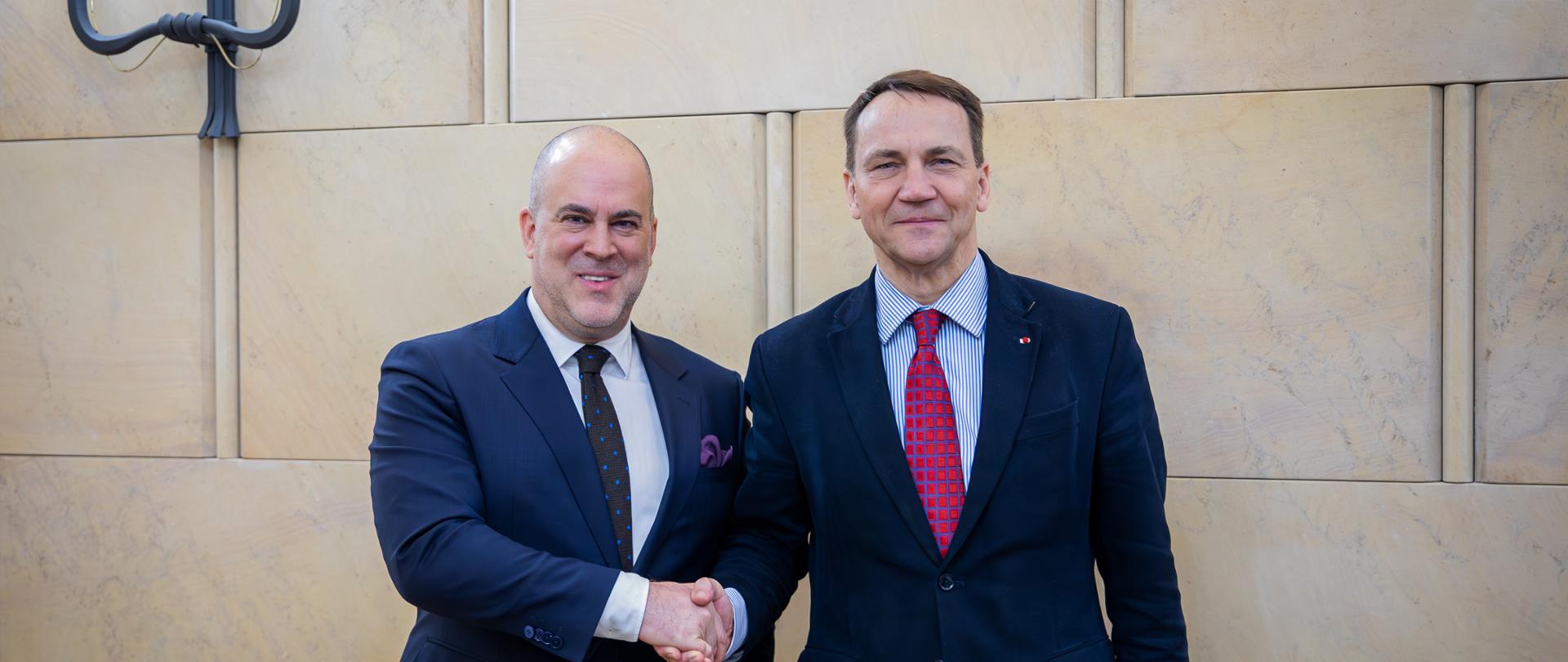 Dwóch mężczyzn pozuje do zdjęcia podając sobie rękę