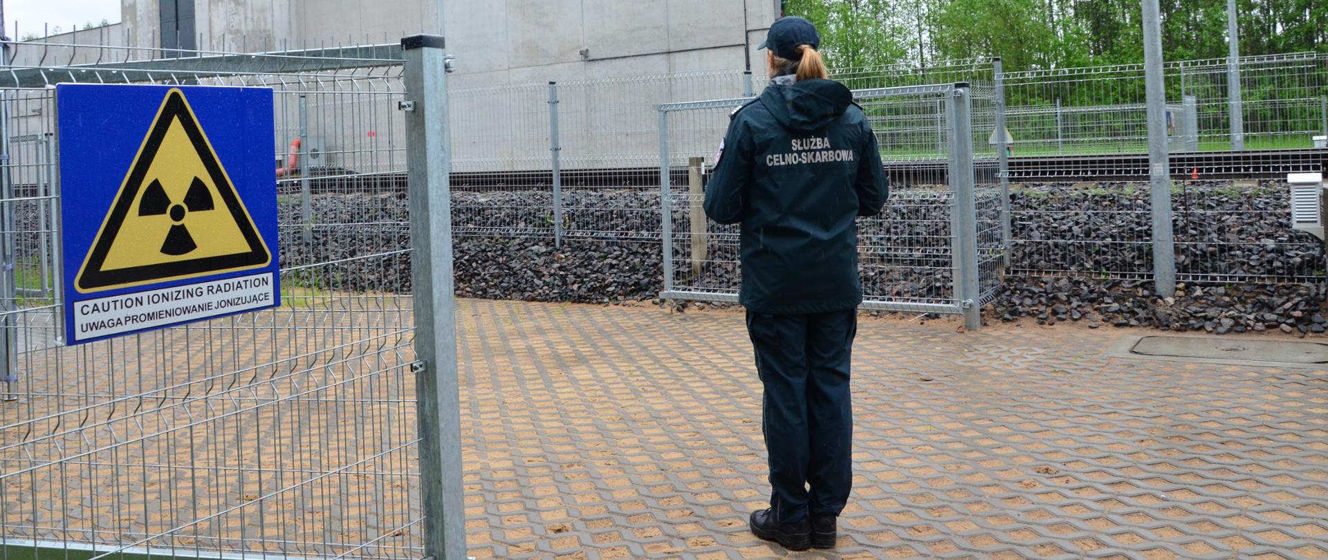 Funkcjonariuszka Służby Celno-Skarbowej stoi przed urządzeniem RTG do prześwietlania pociągów