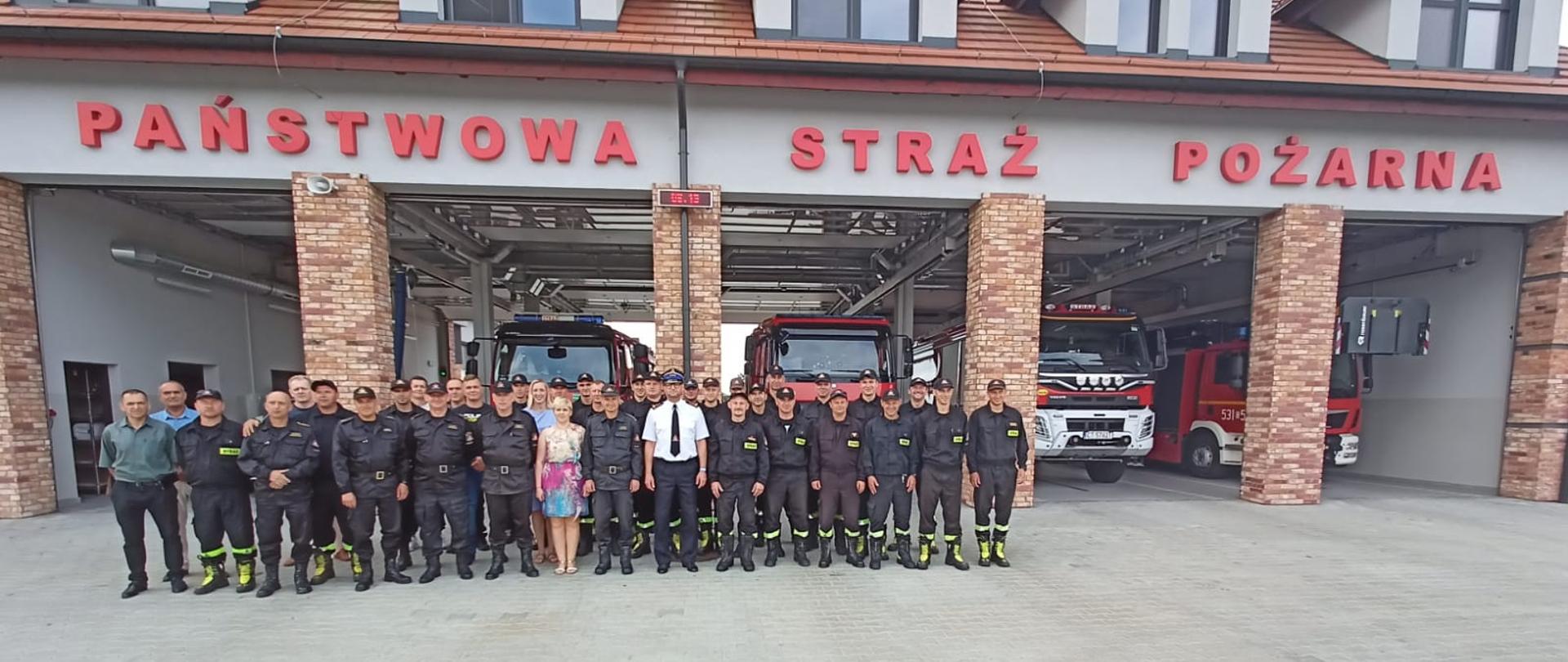 Na tle budynku Komendy Powiatowej Państwowej Straży Pożarnej w Świeciu stoją funkcjonariusze, pracownicy cywilni oraz emeryci Komendy Powiatowej Państwowej Straży Pożarnej w Świeciu. 