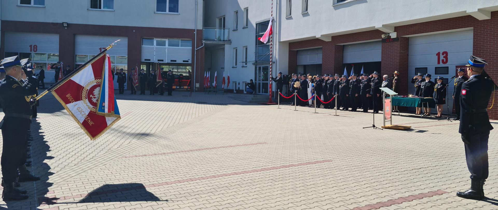 Zdjęcie przedstawia stojących strażacy ze sztandarami ubrani w mundury OSP, goście honorowi i zaproszenie w mundurach oraz osoby cywilne