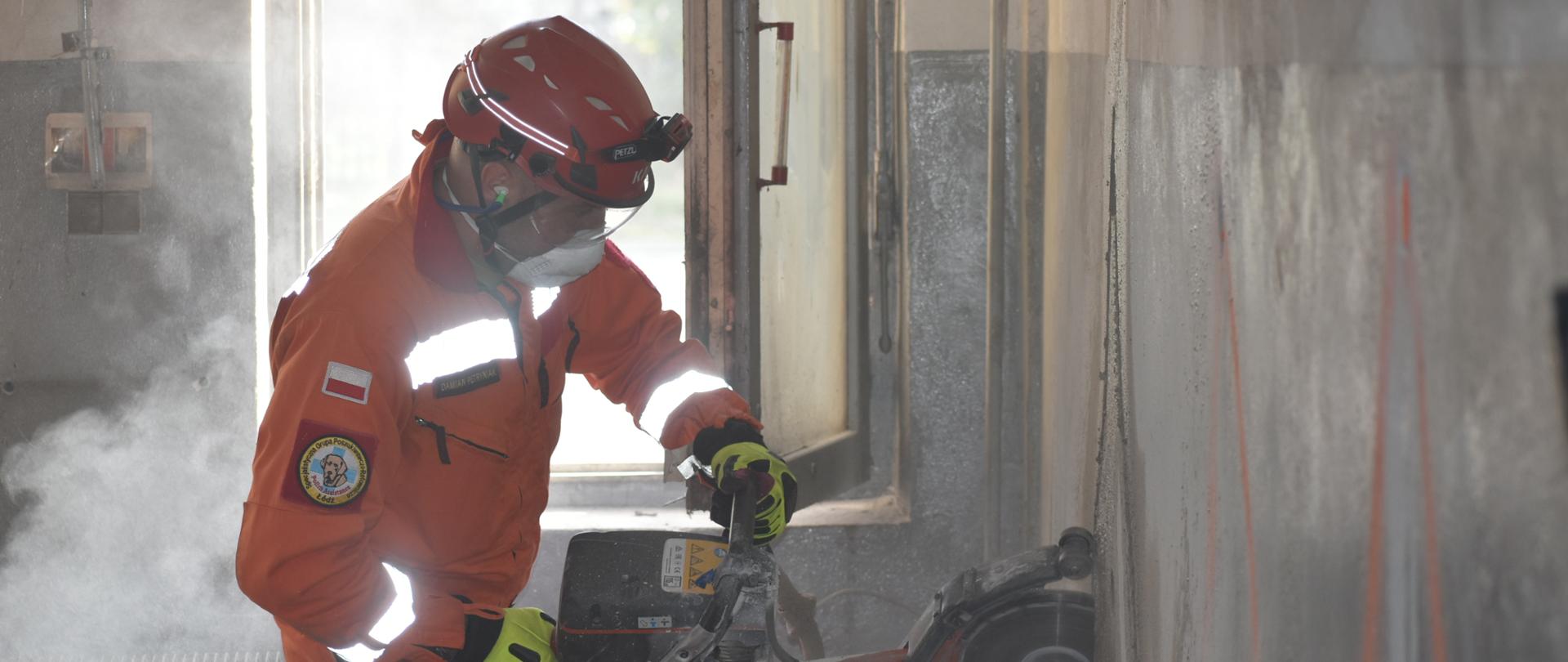 Strażak z piłą tarczową w ręku wycina otwór w ścianie