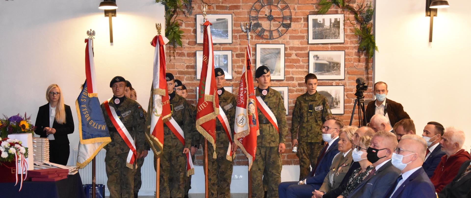 Na zdjęciu znajdują się poczty sztandarowe Związku Sybiraków i Związku Kombatantów i Byłych Więźniów Politycznych RP. Przed pocztami, po prawej stronie zdjęcia znajduje się część widowni. 