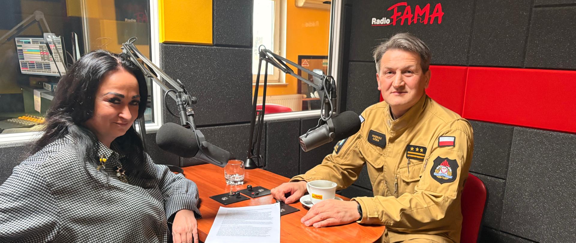 Fotografia przedstawia Komendanta Miejskiego Państwowej Straży Pożarnej w Kielcach st. bryg. Mariusza Górę w redakcji Radia Fama wraz z gospodarzem programu Panią redaktor Anetą Czaban