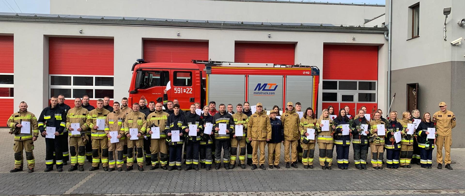 Zdjecie grupowe strażaków na tle komendy