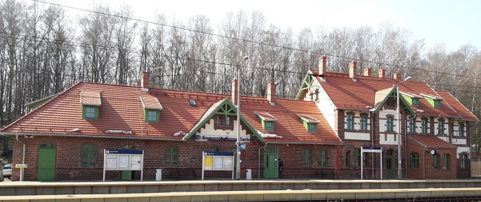 Zdjęcie przedstawia dworzec kolejowy w Boguszowie Gorcach, nowy obiekt oddany do użytku pasażerów, jest zbudowany z czerwonej cegły, ma czerwony dach, zielone drzwi i okiennice.