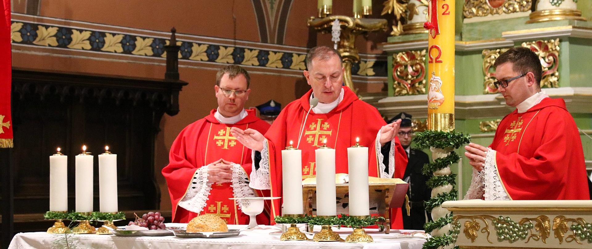 Widok trzech księży koncelebrujących Mszę Świętą przy ołtarzu.