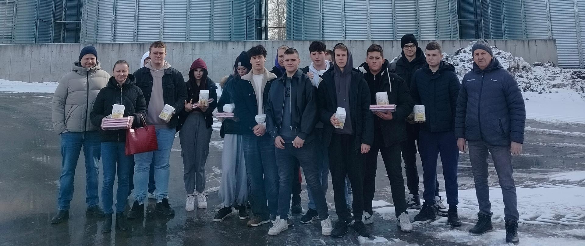 Zdjęcie grupowe uczniów ZSCKR w Rudce na tle silosów zbożowych.