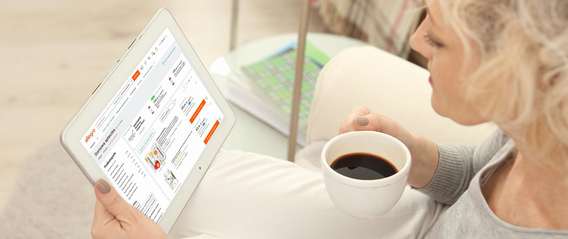 kobieta z kubkiem kawy w ręku patrząca na tablet portalu allegro