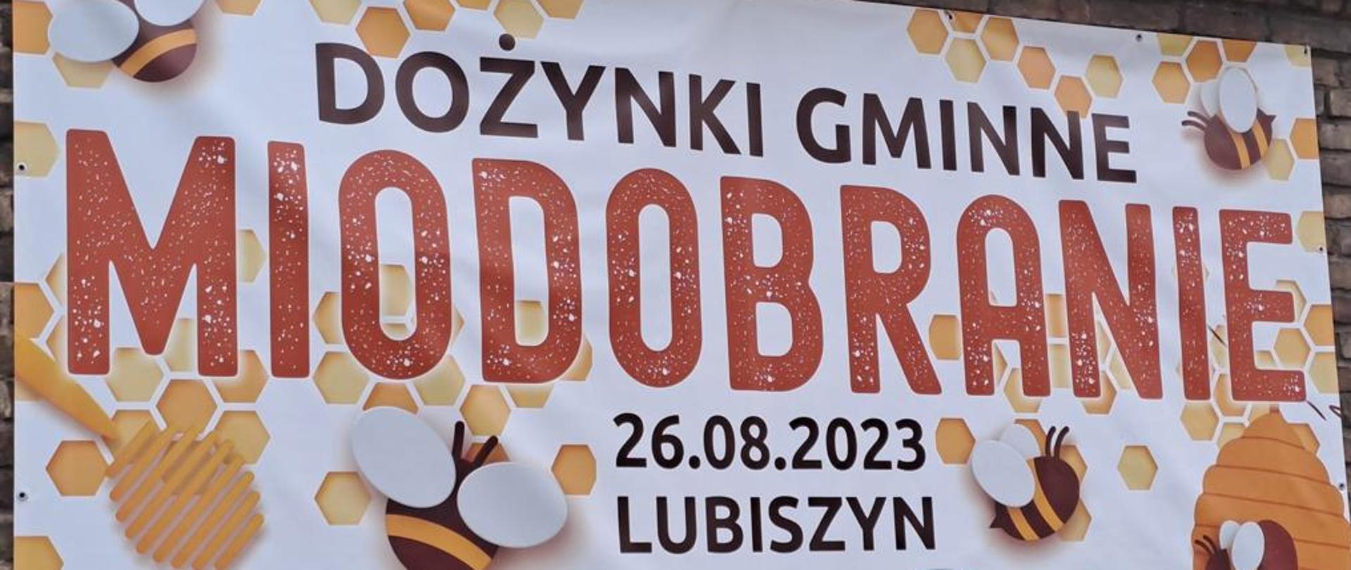 Duży plakat wiszący na ścianie z cegły. Z napisem Dożynki gminne Miodobranie 26.08.2023 Lubiszyn. W tle rysunki pszczół. Na dole obok napisu gmina Lubiszyn logo gminy 