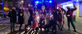 Grupa organizująca akcję na wspólnym zdjęciu ,w tym Święty Mikołaj i strażacy. W tle kosz drabiny mechanicznej