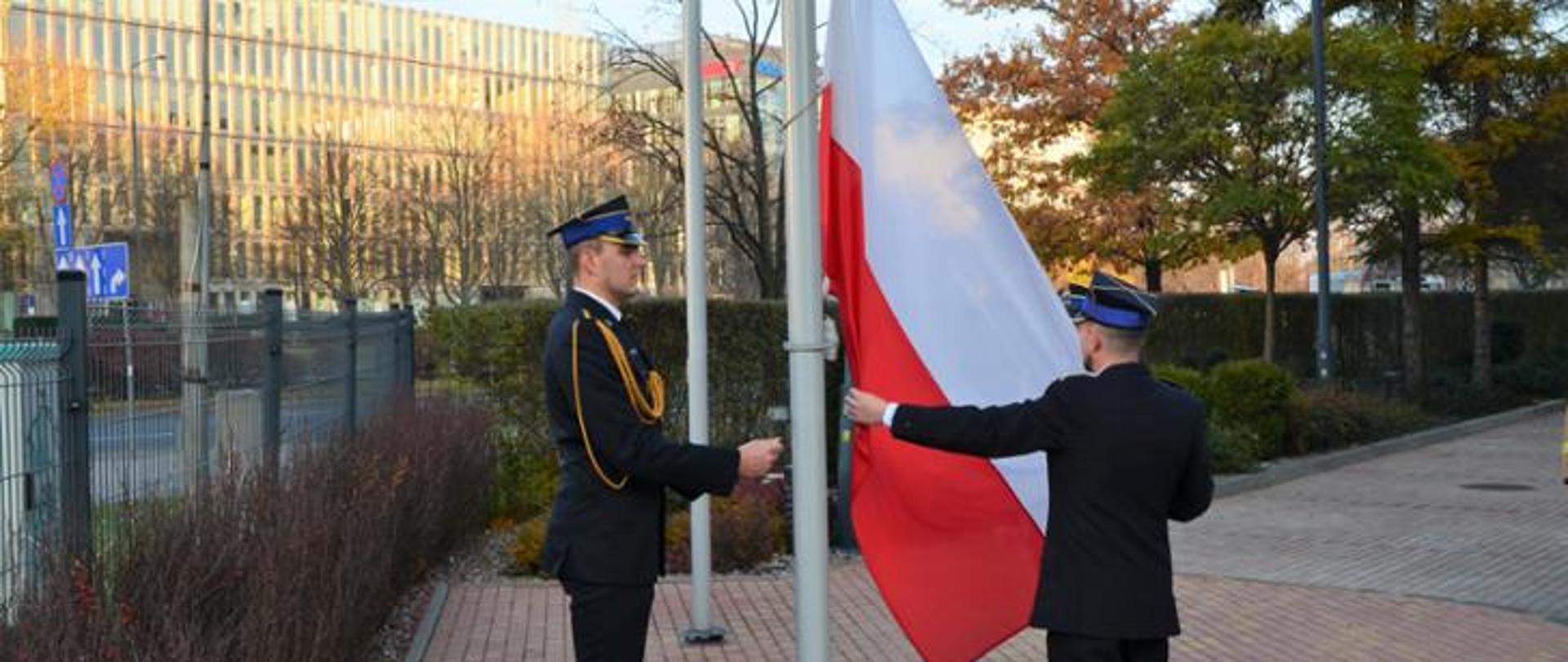 Podniesienie flagi na maszcie przez dwóch funkcjonariuszy PSP