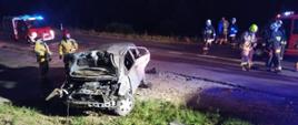 Noc. Ciemno. Na zdjęciu widnieją strażacy podczas akcji związanej z wypadkiem samochodu osobowego. 
