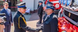 Na zdjęciu widać Pomorskiego Komendanta Wojewódzkiego gratulującego dwóm członkom Ochotniczej Straży Pożarnej pozyskania nowego samochodu ratowniczo-gaśniczego.