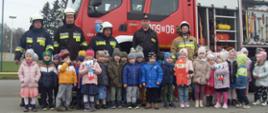 Zdjęcie grupowe dzieci wraz z druhami OSP oraz funkcjonariuszem PSP na tle wozu strażackiego