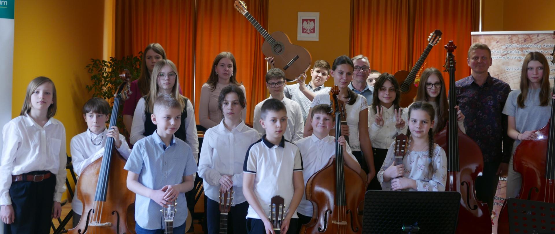 Uczniowie z instrumentami i ich nauczyciele pozują do zdjęcia