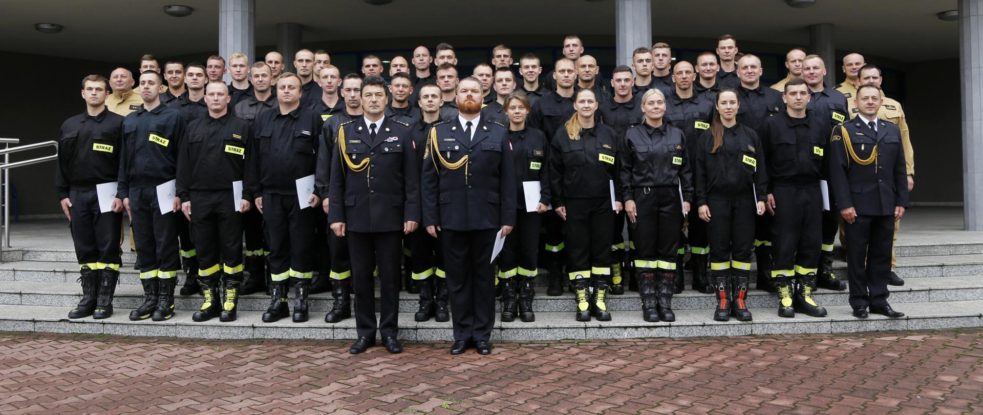 Grupowe zdjęcie uczestników szkolenia podstawowego w zawodzie strażak w towarzystwie Komendanta Centralnej Szkoły PSP oraz przedstawicieli funkcjonariuszy CS PSP