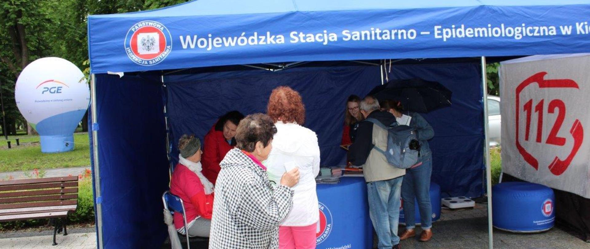 Seniorzy pod namiotem profilaktyczno-informacyjnym WSSE, którym przedstawiciele Oddziału Promocji Zdrowia i Oświaty Zdrowotnej wykonują pomiar ciśnienia tętniczego krwi oraz analizę składu ciała.