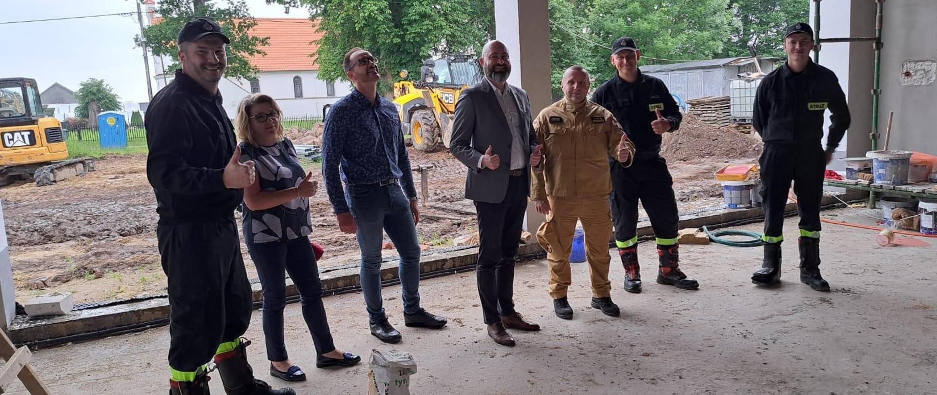 Zdjęcie zrobione w budowanym garażu bojowym remizy OSP Wielkie Wierzno. Na zdjęciu stoją strażacy oraz Burmistrz Fromborka 