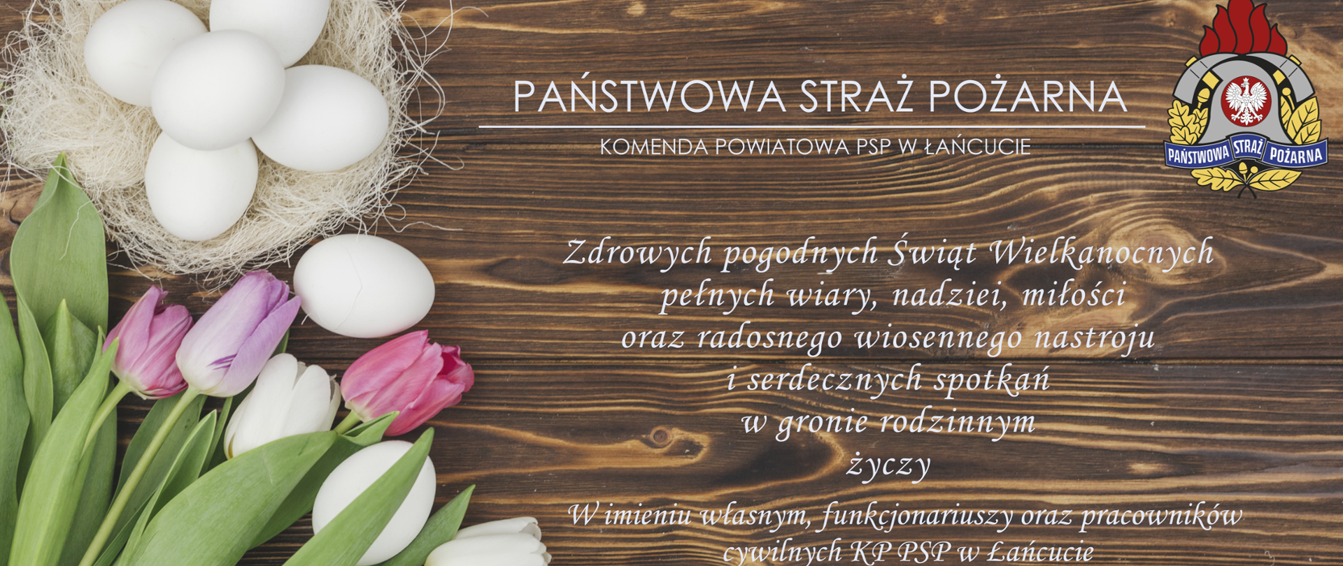 Obraz przedstawia kartkę z życzeniami z okazji Świąt Wielkanocnych. Po lewej stronie znajdują się tulipany leżące na desce oraz jajka Wielkanocne. Na środkowej części znajdują się życzenia podpisane przez Komendanta Powiatowego Państwowej Straży Pożarnej w Łańcucie.