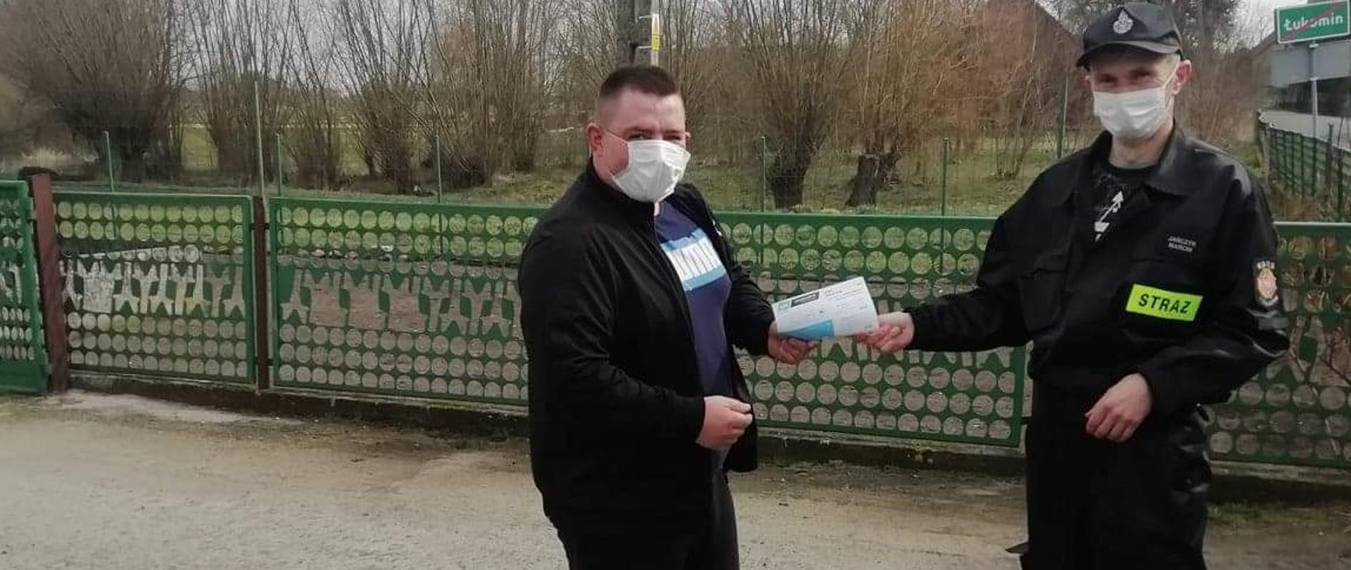 Druh OSP Kołczyn przekazuje ulotki dotyczące szczepienia