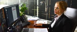 Zastępca Głównego Inspektora Transportu Drogowego Joanna Smolińska siedzi przed komputerem i bierze udział w spotkaniu on-line z przewoźnikami w ramach Społecznej Rady Konsultacyjnej. Na biurku leżą dokumenty.
