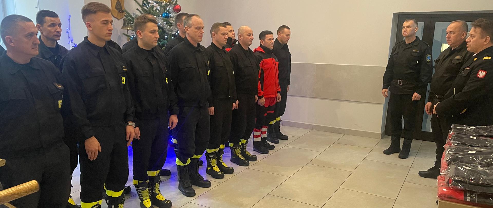 Zmiana służbowa JRG 8 ustawiona w dwuszeregu. Przed nimi Mazowiecki Komendant Wojewódzki, Zastępca Komendanta Miejskiego PSP m. st. Warszawy oraz Dowódca JRG 8.