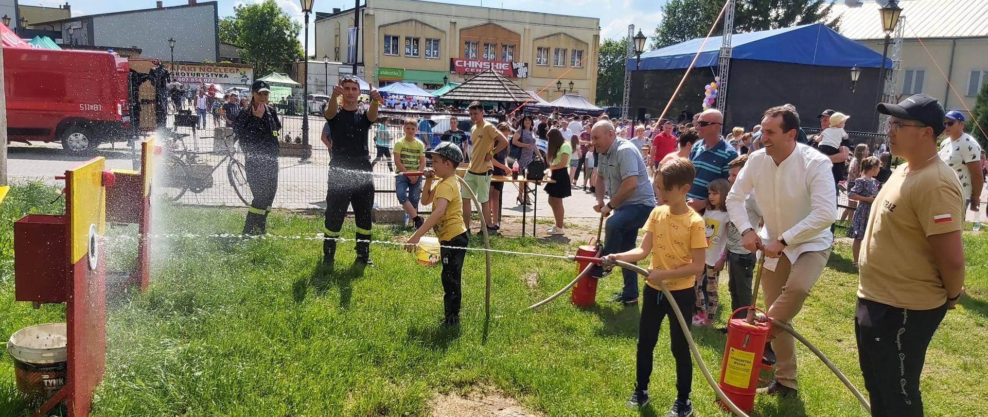 Dzieci leją wodę z hydronetek do celu na imprezie plenerowej