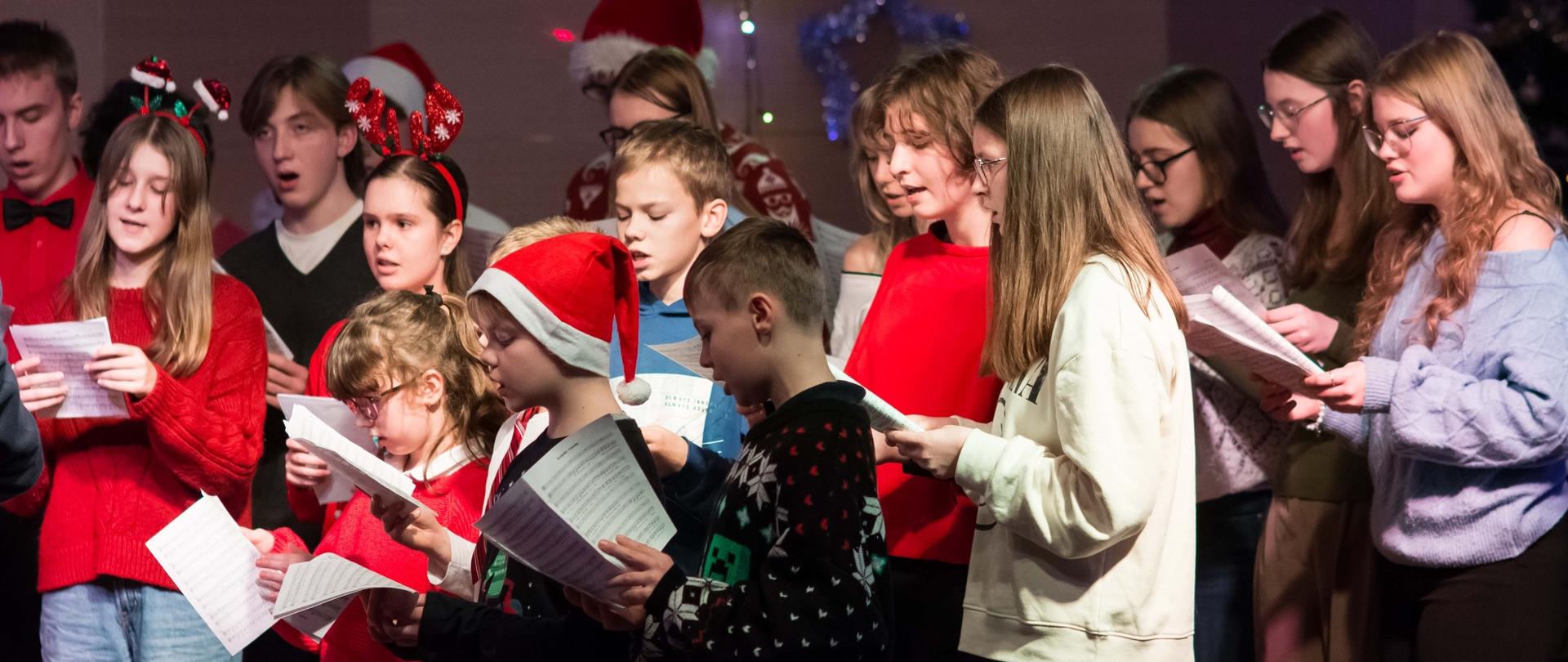 zdjęcie przedstawia część chóru szkolnego na scenie sali koncertowej podczas wykonania utworu, ujęcie z bliska