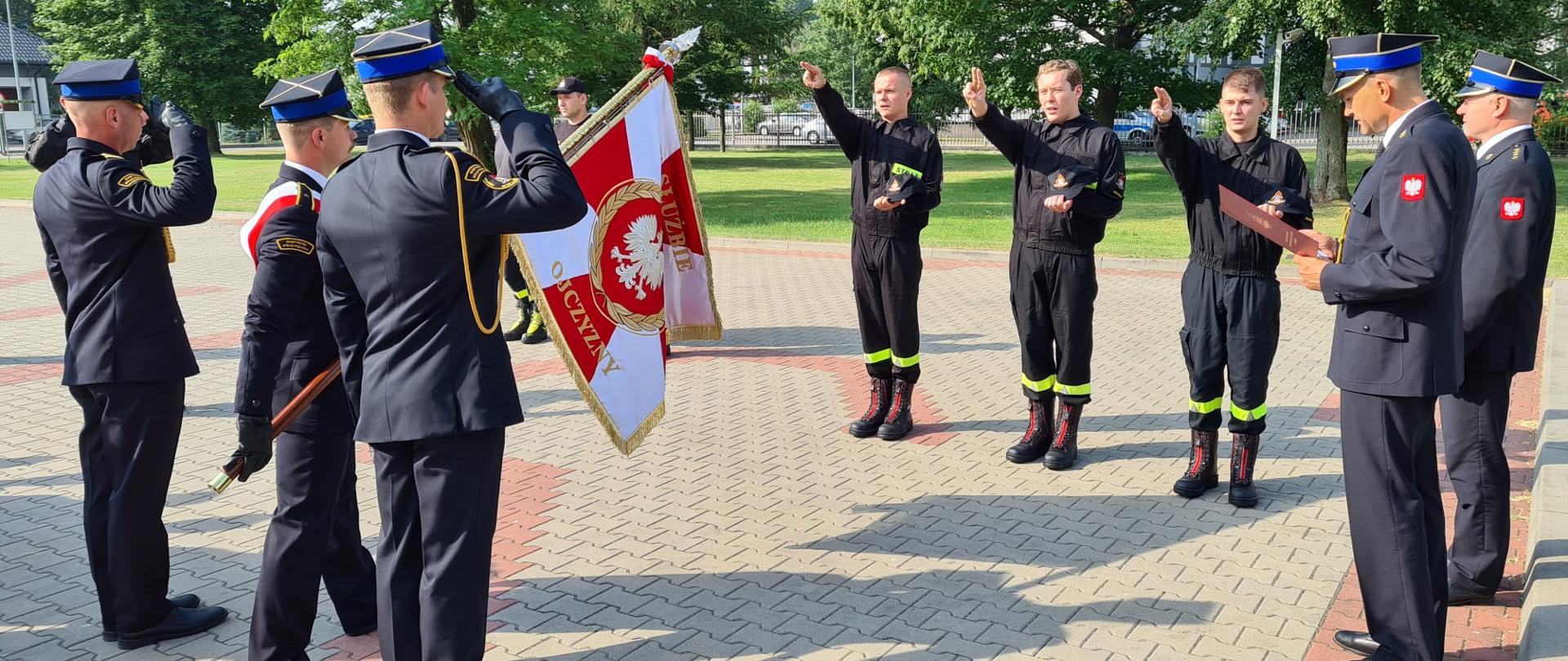 Nowi strażacy składają ślubowanie na sztandar Komendy na placu.