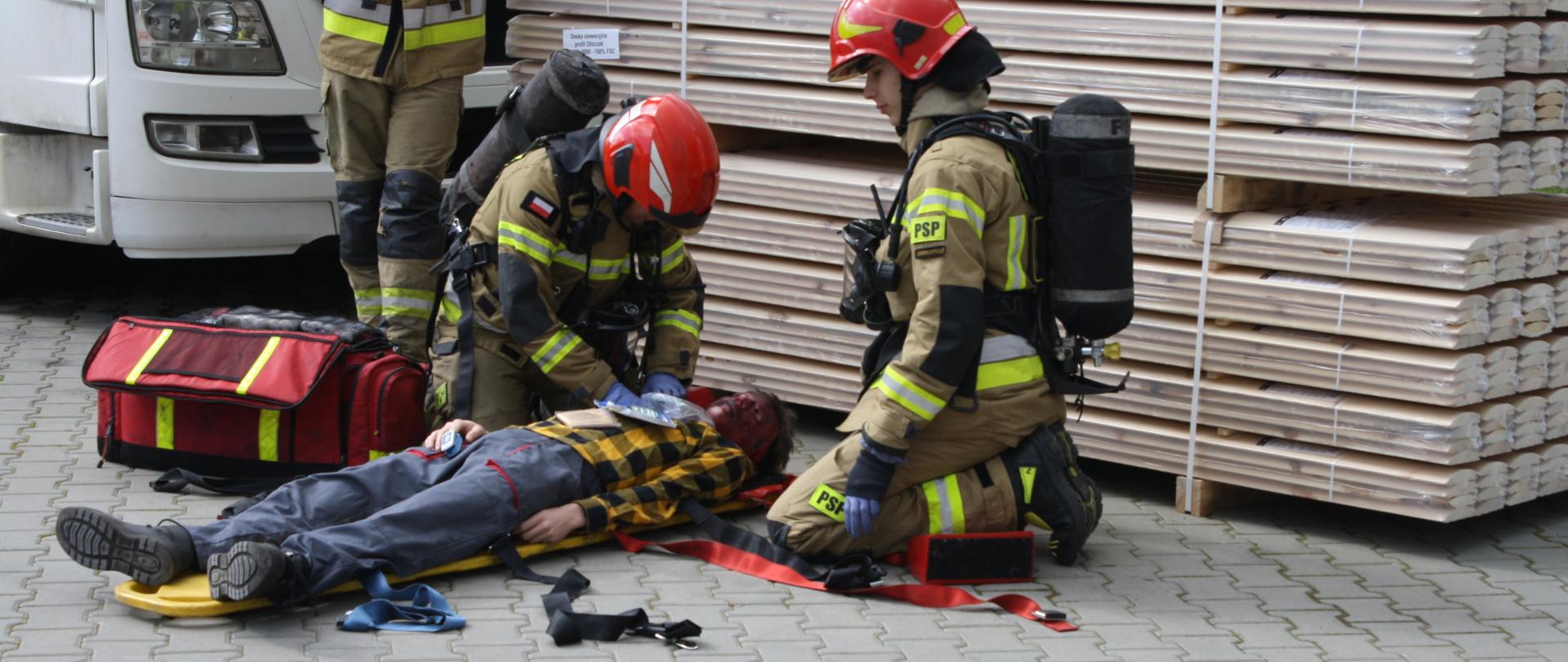 Ratownicy zaopatrujący poszkodowaną osobę na desce ratowniczej