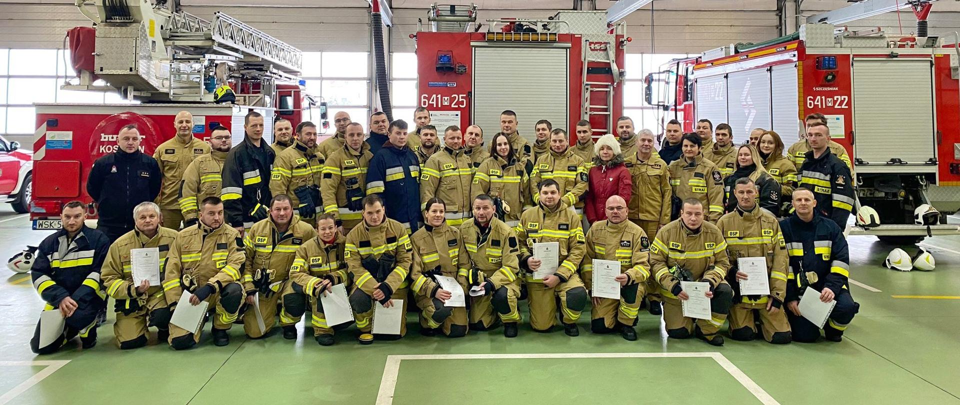 Zakończenie trzeciego szkolenia podstawowego strażaka ratownika OSP 2023 - wspólne zdjęcie w garażu JRG