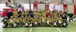 Zakończenie trzeciego szkolenia podstawowego strażaka ratownika OSP 2023 - wspólne zdjęcie w garażu JRG