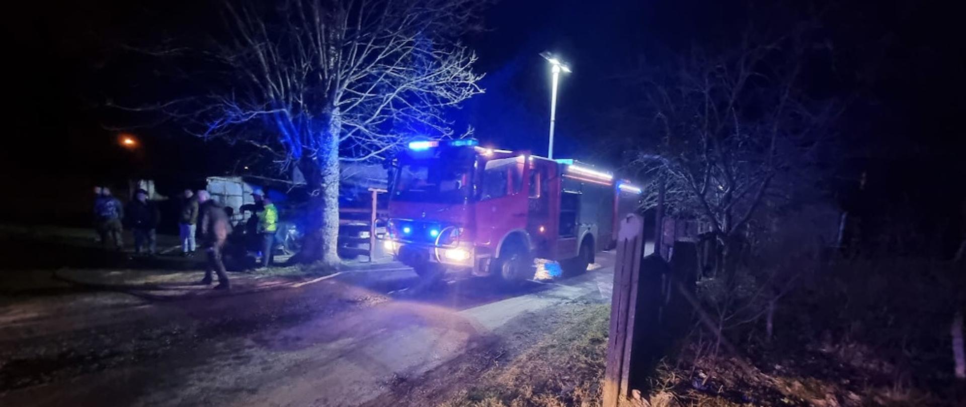 Pożar samochodu i garażu w miejscowości Biały Bór - na pierwszym planie widać samochód ratowniczo-gaśniczy z włączonymi światłami błyskowymi