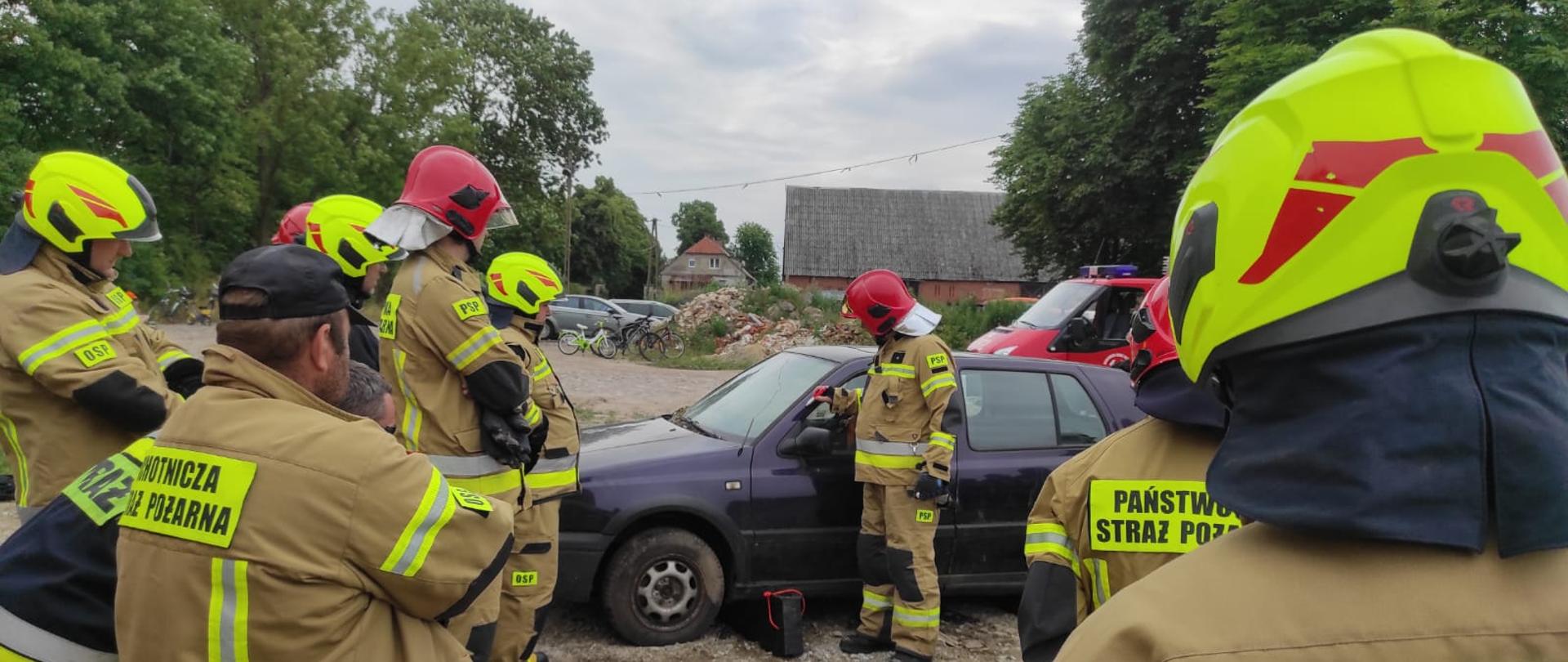 Na zdjęciu strażacy w umundurowaniu bojowym ćwiczący techniki ratownicze na wrakach pojazdów. Używają sprzętu hydraulicznego - nożyce, rozpieracze. 