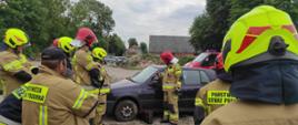 Na zdjęciu strażacy w umundurowaniu bojowym ćwiczący techniki ratownicze na wrakach pojazdów. Używają sprzętu hydraulicznego - nożyce, rozpieracze. 