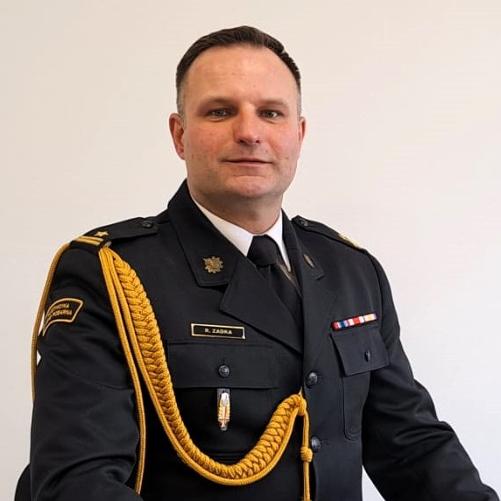 na zdjęciu mł. bryg. Rafał Zadka - Zastępca Komendanta Powiatowego PSP w Oleśnicy w pozycji siedzącej w umundurowaniu galowym
